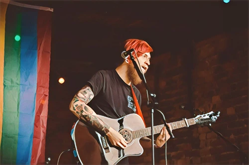 person on a music stage, holding an acoustic guitar